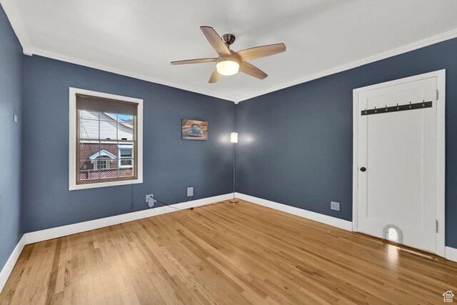 spare room with baseboards, wood finished floors, ceiling fan, and crown molding