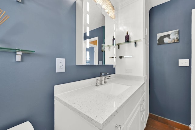 half bathroom with baseboards, vanity, and toilet