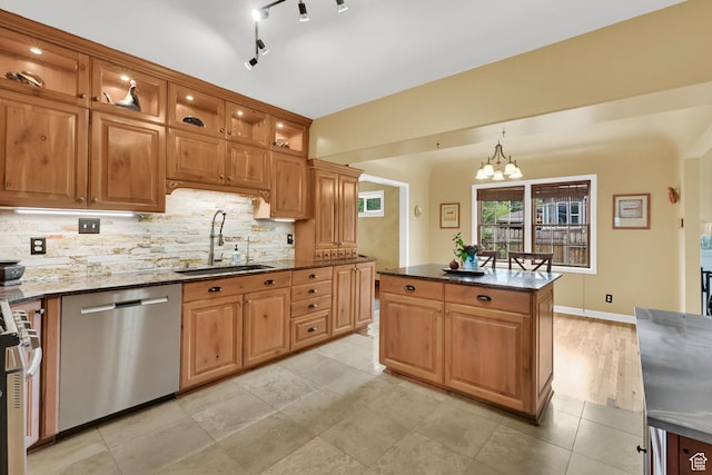 kitchen featuring appliances with stainless steel finishes, a sink, backsplash, dark stone countertops, and glass insert cabinets