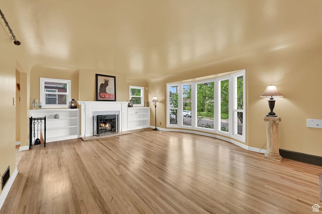 unfurnished living room with a fireplace, wood finished floors, and baseboards