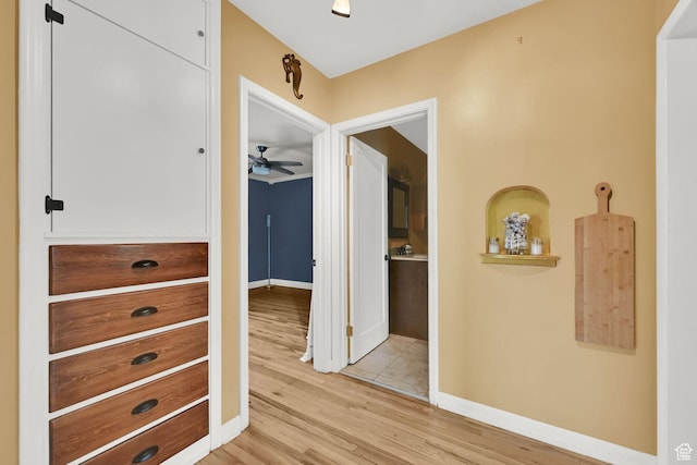 hall with light wood-style flooring and baseboards