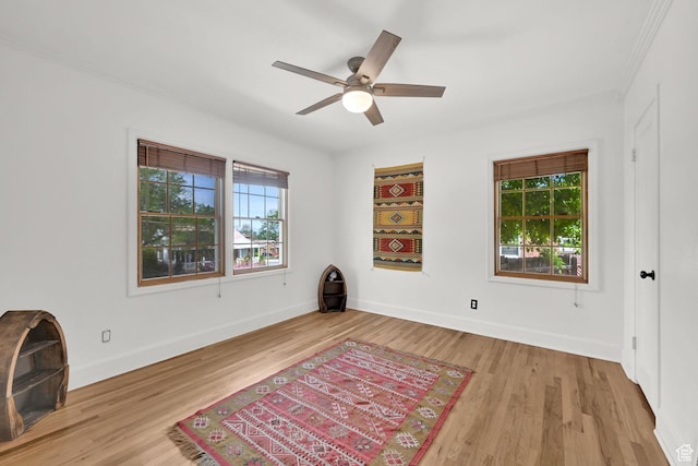 spare room featuring healthy amount of natural light, wood finished floors, baseboards, and crown molding