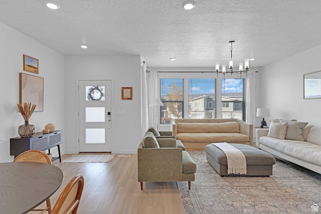 living room with a wealth of natural light, a chandelier, wood finished floors, and a textured ceiling