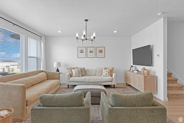 living area with recessed lighting, an inviting chandelier, light wood-type flooring, and a textured ceiling