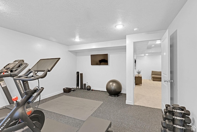exercise area with a textured ceiling, carpet flooring, and baseboards