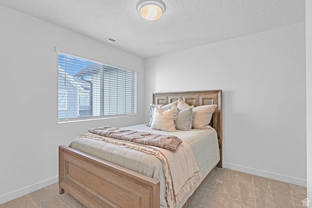 bedroom with light colored carpet, a textured ceiling, baseboards, and visible vents