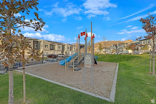 community playground featuring a lawn, fence, and a residential view