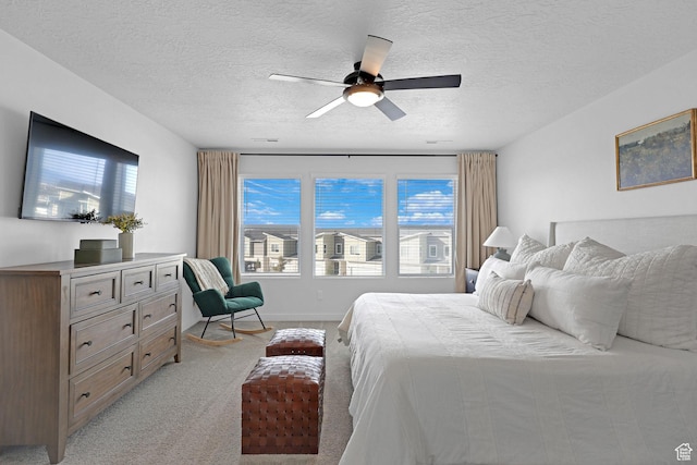 bedroom featuring a textured ceiling, light carpet, and ceiling fan