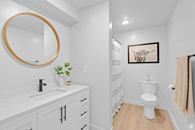 full bath with a textured ceiling, toilet, baseboards, vanity, and wood finished floors