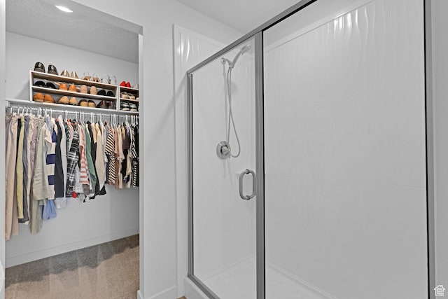 full bathroom featuring a spacious closet, a stall shower, and baseboards