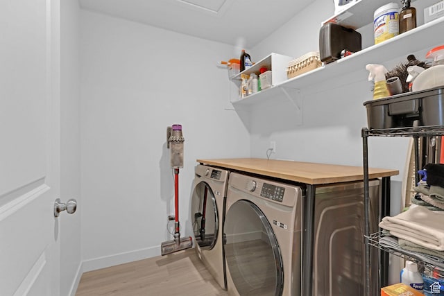 laundry area with laundry area, washer and clothes dryer, baseboards, and light wood-style floors