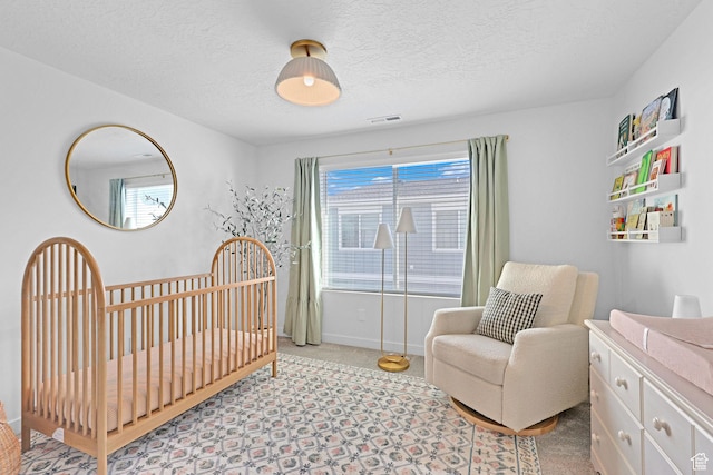bedroom featuring multiple windows, a nursery area, visible vents, and a textured ceiling