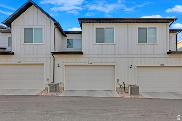 townhome / multi-family property with cooling unit, board and batten siding, and a garage