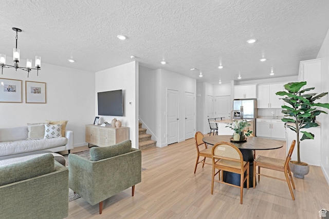 dining area with light wood-style flooring, a textured ceiling, a notable chandelier, and recessed lighting