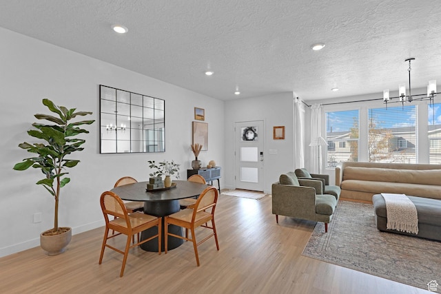 dining area with a chandelier, light wood-type flooring, a textured ceiling, baseboards, and recessed lighting