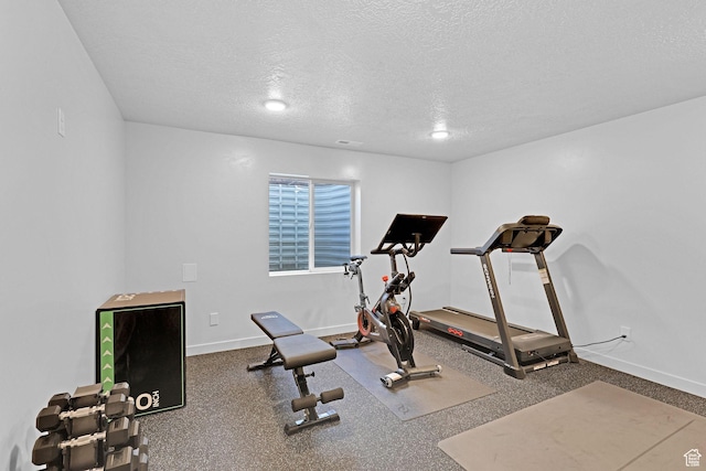 workout area featuring a textured ceiling and baseboards