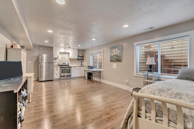 13623 S Blayde Dr W, Herriman, UT 84096 - bedroom with light wood finished floors, freestanding refrigerator, visible vents, baseboards, and recessed lighting