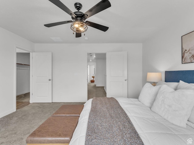 carpeted bedroom with a spacious closet, baseboards, and a ceiling fan