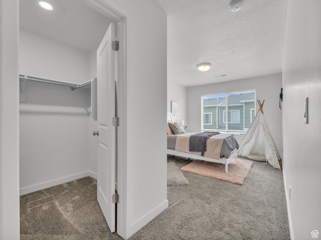carpeted bedroom with a textured ceiling and baseboards