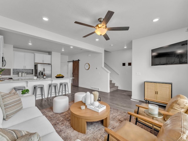 living area with dark wood finished floors, visible vents, a barn door, and recessed lighting