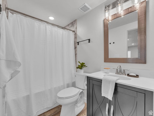 full bathroom featuring toilet, wood finished floors, a shower with shower curtain, visible vents, and vanity