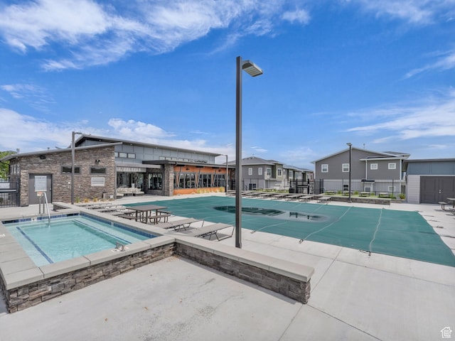 pool with a hot tub, a patio area, and fence