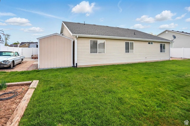 back of house with a fenced backyard, a storage unit, a yard, and an outbuilding