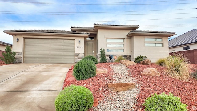 prairie-style home featuring stone siding, stucco siding, driveway, and an attached garage
