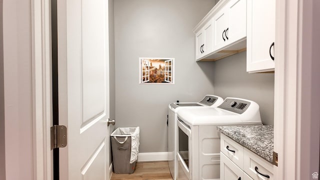 clothes washing area featuring cabinet space, baseboards, washer and dryer, and light wood-style flooring