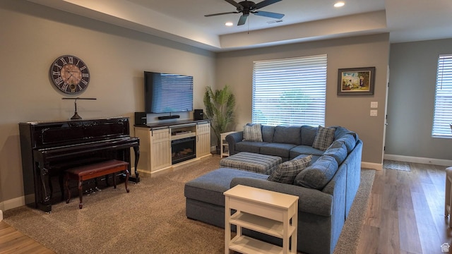 living area featuring a ceiling fan, visible vents, baseboards, a raised ceiling, and recessed lighting