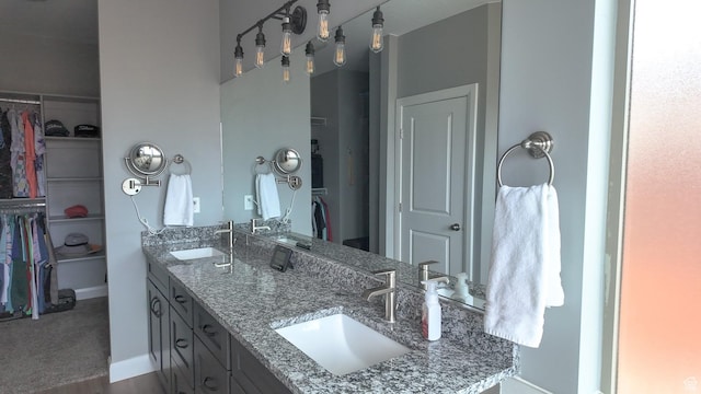 full bath featuring a spacious closet, double vanity, and a sink