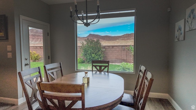 dining space featuring a chandelier, wood finished floors, baseboards, and a healthy amount of sunlight