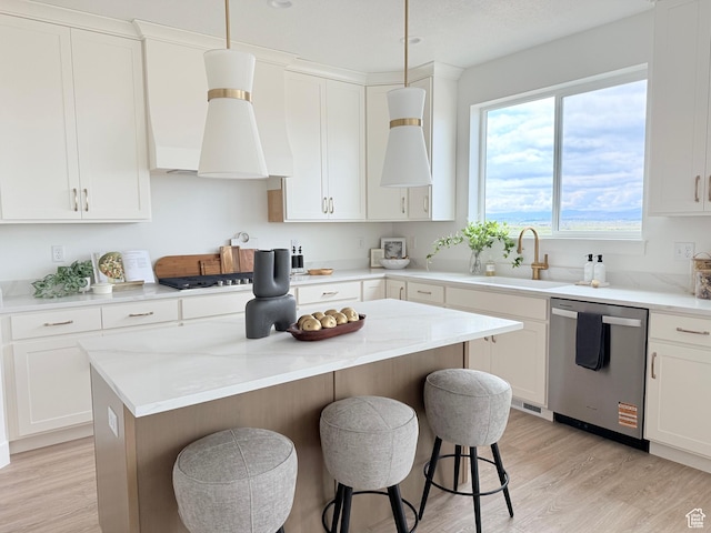 kitchen with stainless steel appliances, a sink, a breakfast bar, light wood-style flooring, and a center island