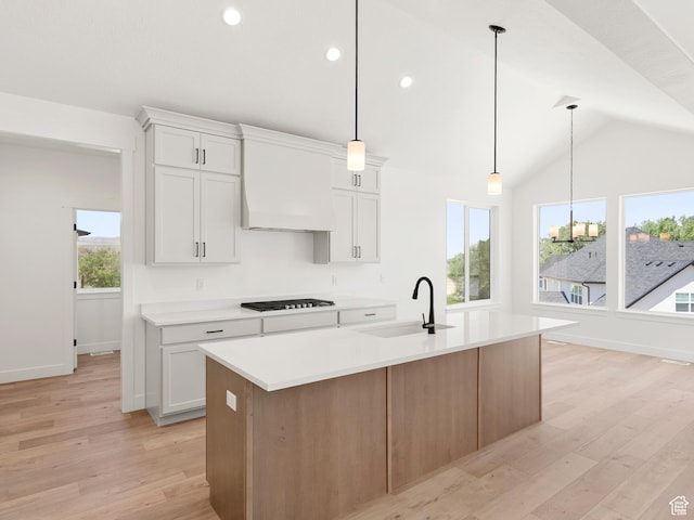 1336 W 800 S Unit 22, Spanish Fork, UT 84660 - kitchen featuring premium range hood, light countertops, light wood-style flooring, vaulted ceiling, and a kitchen island with sink