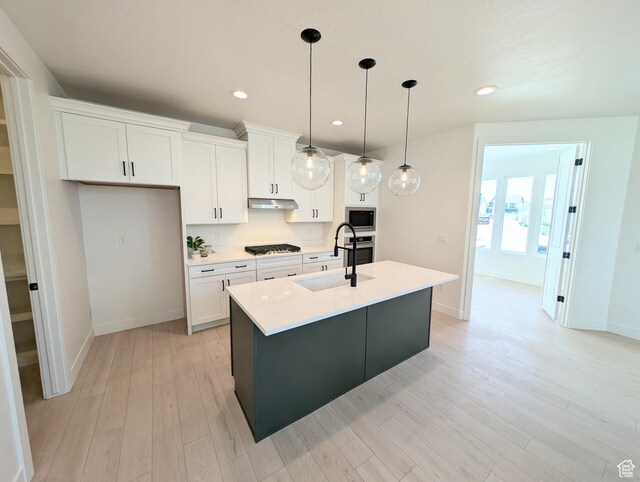 6967 W Lake Ave S Unit 324, South Jordan, UT 84009 - kitchen featuring a sink, appliances with stainless steel finishes, a center island with sink, white cabinetry, and baseboards