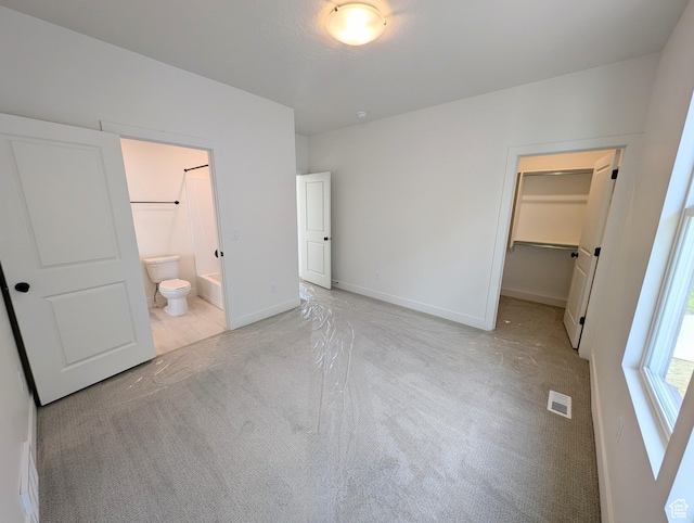 unfurnished bedroom featuring light carpet, a closet, baseboards, visible vents, and a spacious closet