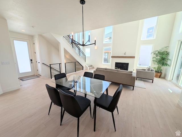 6967 W Lake Ave S Unit 324, South Jordan, UT 84009 - dining space with stairway, light wood finished floors, a chandelier, a fireplace, and baseboards