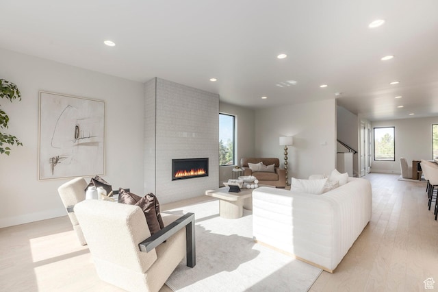 living room featuring a large fireplace, stairs, baseboards, and recessed lighting