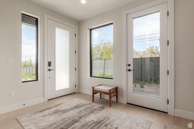entryway with baseboards, light wood-style flooring, and a healthy amount of sunlight