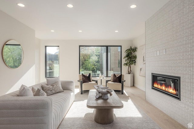 living room with light wood-type flooring, a fireplace, a healthy amount of sunlight, and recessed lighting