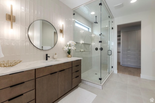 full bathroom featuring tile patterned floors, tile walls, a shower stall, backsplash, and vanity
