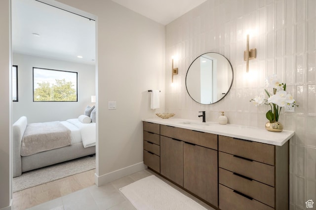 bathroom with ensuite bathroom, tile patterned flooring, baseboards, tasteful backsplash, and vanity