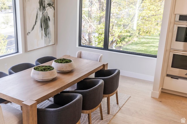 dining space featuring baseboards and light wood finished floors