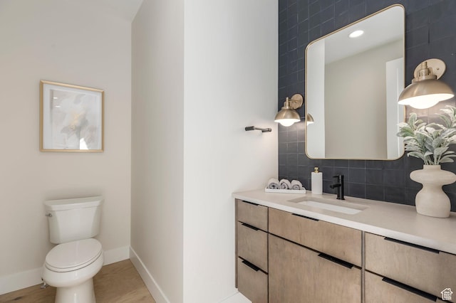 bathroom featuring vanity, toilet, backsplash, and baseboards