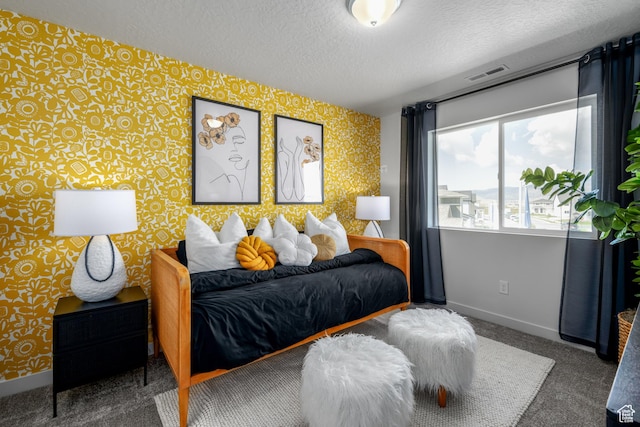 carpeted bedroom featuring baseboards, visible vents, wallpapered walls, and a textured ceiling