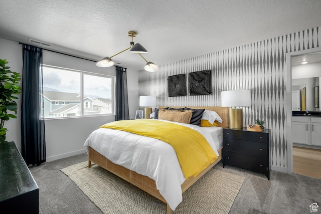 bedroom with baseboards, light carpet, visible vents, and a textured ceiling