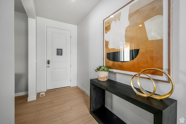 foyer entrance with visible vents, wood finished floors, and baseboards