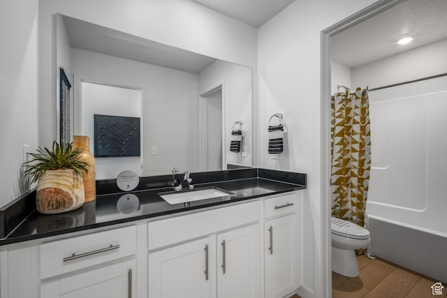 bathroom featuring toilet, vanity, shower / bath combo with shower curtain, and wood finished floors