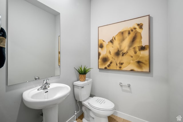 half bathroom featuring toilet, baseboards, and a sink
