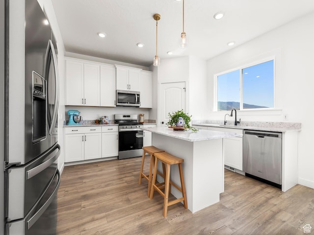 kitchen with recessed lighting, white cabinetry, a kitchen island, and appliances with stainless steel finishes